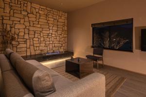 een woonkamer met een bank en een stenen muur bij KOS Restaurant & Hotel in Fujikawaguchiko