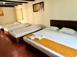 drie bedden in een kamer met bij Hotel Finca la Playa in Villeta