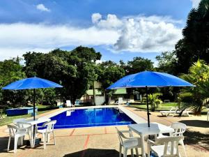 twee tafels en stoelen met parasols naast een zwembad bij Hotel Finca la Playa in Villeta +8 foto's