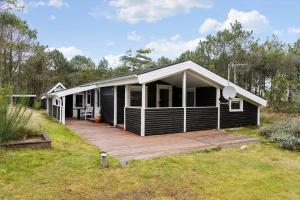 una casa nera con una terrazza in legno in un campo di 873-Thisted-Blamunkevej-67 a Thisted