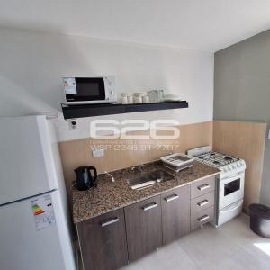 een keuken met een spoelbak, een fornuis en een koelkast bij SANTA TERESITA Depto 4 personas Aire acondicionado Wifi TvCable Parrilla in Santa Teresita
