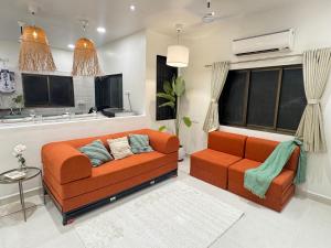 een woonkamer met een oranje bank en een tafel bij AT Alibaug - A Boho Boutique Stay in Alibaug +8 foto's