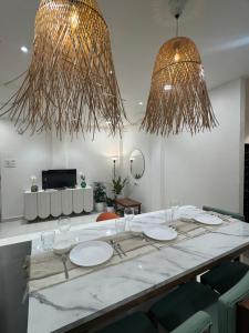 a dining room with a table with chairs and two chandeliers at AT Alibaug - A Boho Boutique Stay in Alibaug