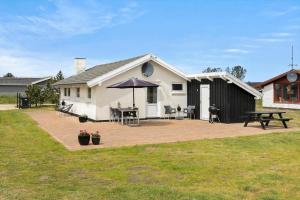 ein weißes Haus mit einem Picknicktisch und einem Sonnenschirm in der Unterkunft 760 Thisted - Pighvarvej 30 in Thisted