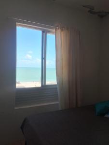 a bedroom with a window with a view of the beach at Apartamento BEIRA MAR - Edifício Mar Del Plata in Itamaracá