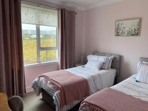 1 Schlafzimmer mit 2 Betten neben einem Fenster in der Unterkunft Tigh-na-Greine in Carloway