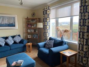 ein Wohnzimmer mit zwei blauen Sofas und einem Fenster in der Unterkunft Tigh-na-Greine in Carloway