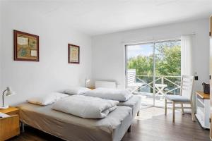 a white bedroom with two beds and a balcony at 204-Vestervig-Lodbjergvej-4 in Vestervig