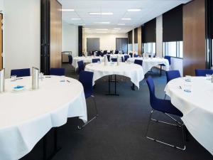 een conferentieruimte met witte tafels en blauwe stoelen bij Mantra MacArthur Hotel in Canberra