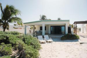 ein Haus am Strand mit zwei Stühlen und einer Veranda in der Unterkunft Beach house Chuchos in Chelem