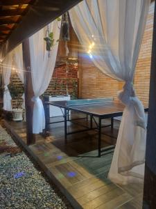 a ping pong table in a room with curtains at Chácara Bela Vista in Itajubá