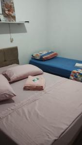 2 Betten in einem Zimmer mit rosa Handtüchern darauf in der Unterkunft Casa da Mariângela in São Gabriel