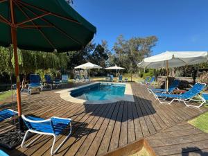 een zwembad met stoelen en parasols op een houten terras bij Las Coloniales in Sauce de Portezuelo