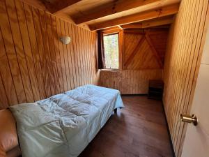 een bed in een houten kamer met een raam bij Domo Algarrobo 1 in San Antonio
