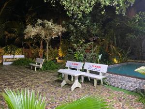 zwei weiße Bänke neben einem Swimmingpool in der Unterkunft Phòng View sân vườn-hồ bơi in Ấp Phú Khương