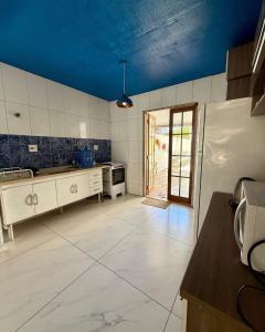 a large kitchen with white appliances and a blue ceiling at Casa completa Av Roberto da Silveira in Paraty