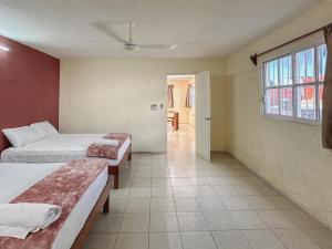 een hotelkamer met twee bedden en een raam bij Sol y Luna Hospedaje in Valladolid