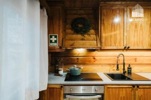 a kitchen with a sink and a stove and wooden cabinets at Chalé Recanto 39 Luxury Mountain Retreat in Penhas da Saúde