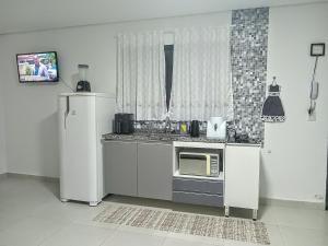 a kitchen with a refrigerator and a microwave at Casa das Cachoeiras in Botucatu