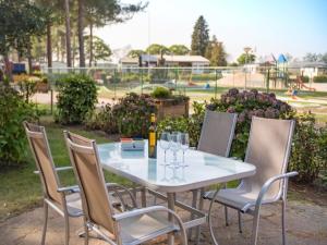 ein Tisch und Stühle mit Weingläsern und ein Spielplatz in der Unterkunft Luxury Forest Lodge with Private Garden in Overbroek