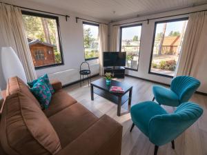 ein Wohnzimmer mit Sofa, Stühlen und Fenstern in der Unterkunft Luxury Forest Lodge with Private Garden in Overbroek