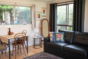 a living room with a black leather couch and a table at Bower On Becket - Couples Retreat in Rye