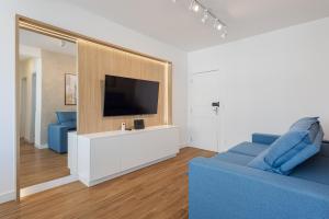 a living room with a blue couch and a tv at Apto Reformado e Moderno com Vista Mar no Centro in Florianópolis