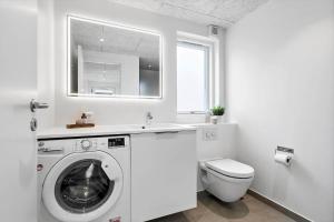 een witte badkamer met een wasmachine en een toilet bij 940-Hvide-Sande-Langsand-169 in Hvide Sande +33 foto's