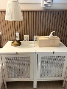 un tavolo bianco con una lampada e una scatola sopra di GreeneStay Sindang DDP Seoul a Seul