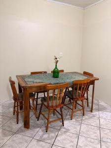 een houten tafel met stoelen en een vaas met bloemen erop bij Chacara do japonês 
