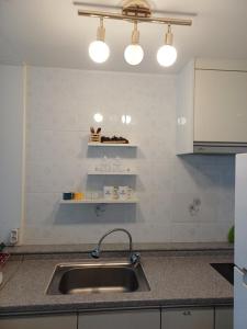 a kitchen with a sink and two lights above it at Melodia Pension in Geoje
