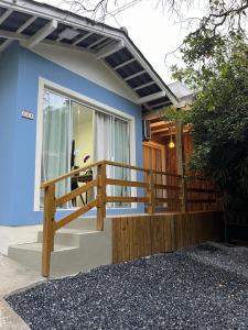 a blue house with a wooden railing on a porch at Casa no Centrinho para 2 pessoas 100m do Mar in Bombinhas