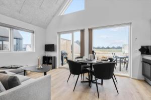 un salon avec une table, des chaises et un canapé dans l'établissement 9951-Hvide-Sande-Langsand-206, à Hvide Sande