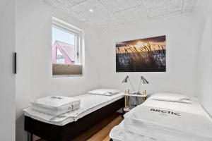 deux lits dans une chambre blanche avec une fenêtre dans l'établissement 9951-Hvide-Sande-Langsand-206, à Hvide Sande