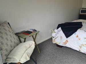 een slaapkamer met een bed en een tafel met een boek bij Lanark Mews in Te Kopuru