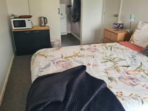 een slaapkamer met een bed en een magnetron op een aanrecht bij Lanark Mews in Te Kopuru