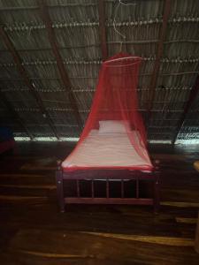 een rood bed met een net erbovenop bij Finca Buena Vida Hostel in Popoyo