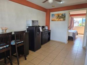 a room with a kitchen with a refrigerator and a table at Loft Rayito de Sol, Zihuatanejo Center with AC in Zihuatanejo