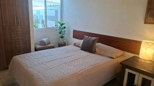 una camera da letto con un letto bianco con testiera in legno di Casa Veta Qro a Villa del Pueblito