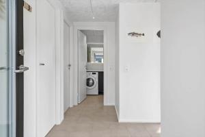 un couloir aux murs blancs et un lave-linge. dans l'établissement 943-Hvide-Sande-Langsand-165, à Hvide Sande