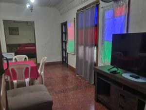 een woonkamer met een televisie en een tafel en stoelen bij Volcano Hostel in León
