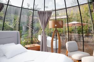 a bedroom with a bed and a large glass window at Cabana Bolha Realeza in Manhuaçu