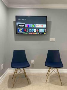 twee blauwe stoelen en een flatscreen-tv aan de muur bij sunset cottage in West Palm Beach