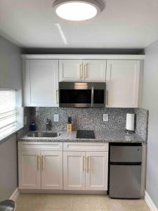 een keuken met witte kasten en een spoelbak bij sunset cottage in West Palm Beach