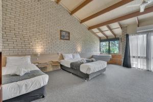 een slaapkamer met twee bedden en een bakstenen muur bij Snobs Creek Motel Eildon in Eildon