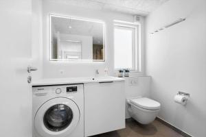 een witte badkamer met een wasmachine en een toilet bij 944-Hvide-Sande-Langsand-143 in Hvide Sande +32 foto's