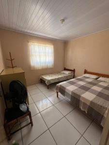 a room with two beds and a chair in it at Recanto do descanso in Pinhal