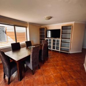 a dining room with a table and chairs and a television at Live, Laugh, Lodge - Central 3x2 in Kalgoorlie