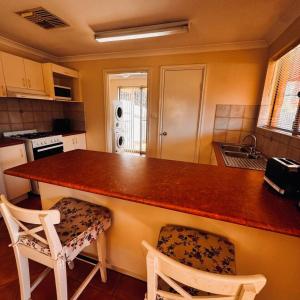 a kitchen with a counter top and two chairs at Live, Laugh, Lodge - Central 3x2 in Kalgoorlie