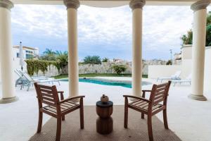 two chairs and a table on a porch with a pool at Luxury Villa Retreat, Pool in Cabo San Lucas